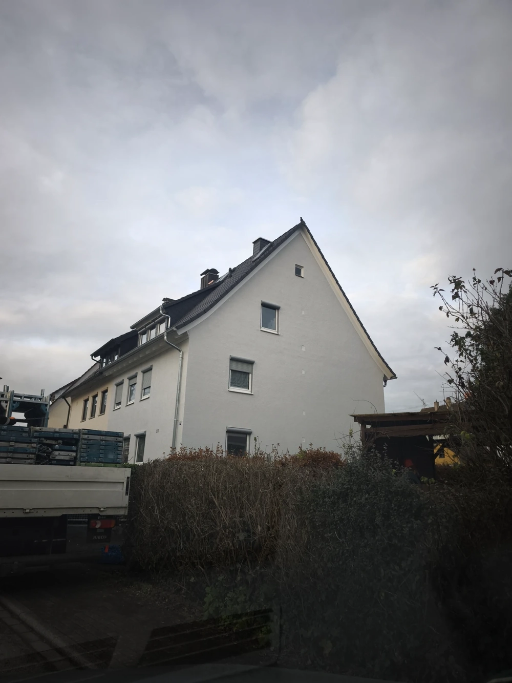 Weißes Mehrfamilienhaus mit neu eingedecktem Ziegeldach nach Dachsanierung
