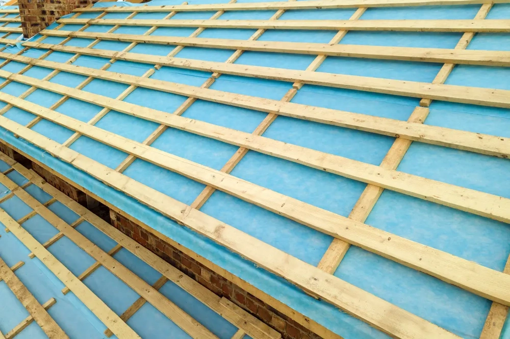 Aufgebrachte blaue Dampfsperre mit aufgenagelten Holzlatten auf Dachkonstruktion
