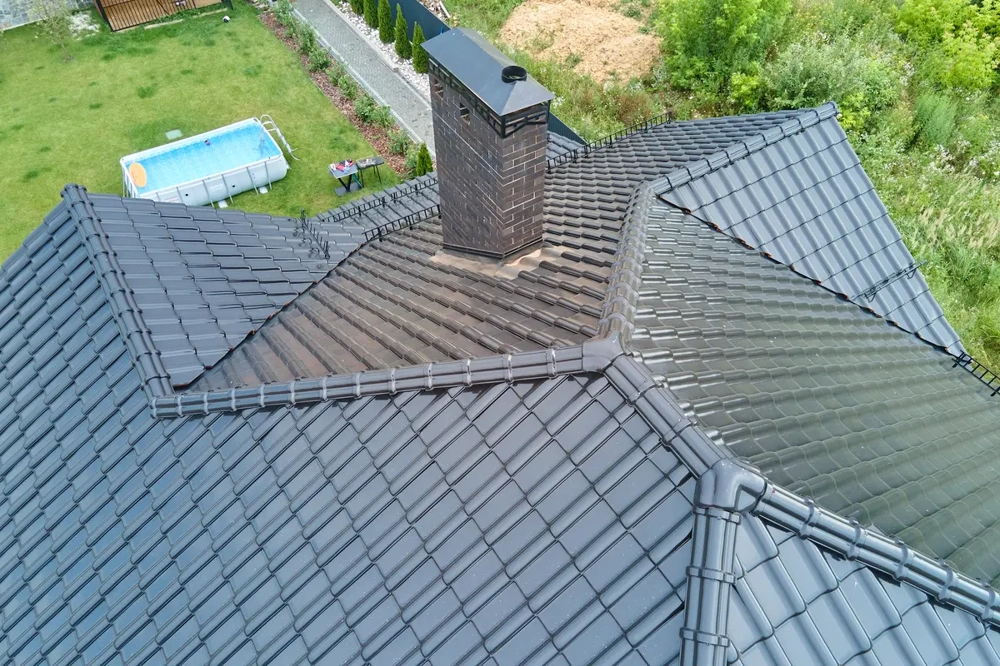 Frisch ausgeführte Ziegeldacheindeckung auf grauem Dach mit Schornstein, Blick von oben