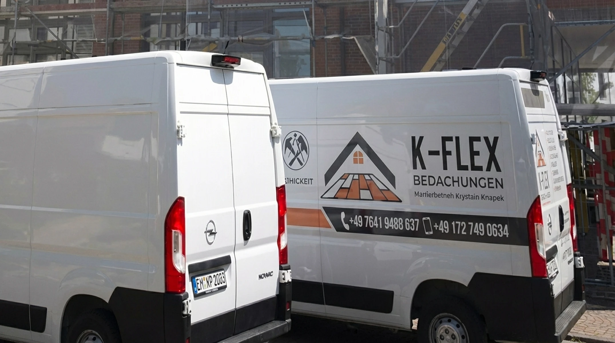 Zwei weiße Firmenfahrzeuge mit Bedachungslogo vor eingerüstetem Gebäude