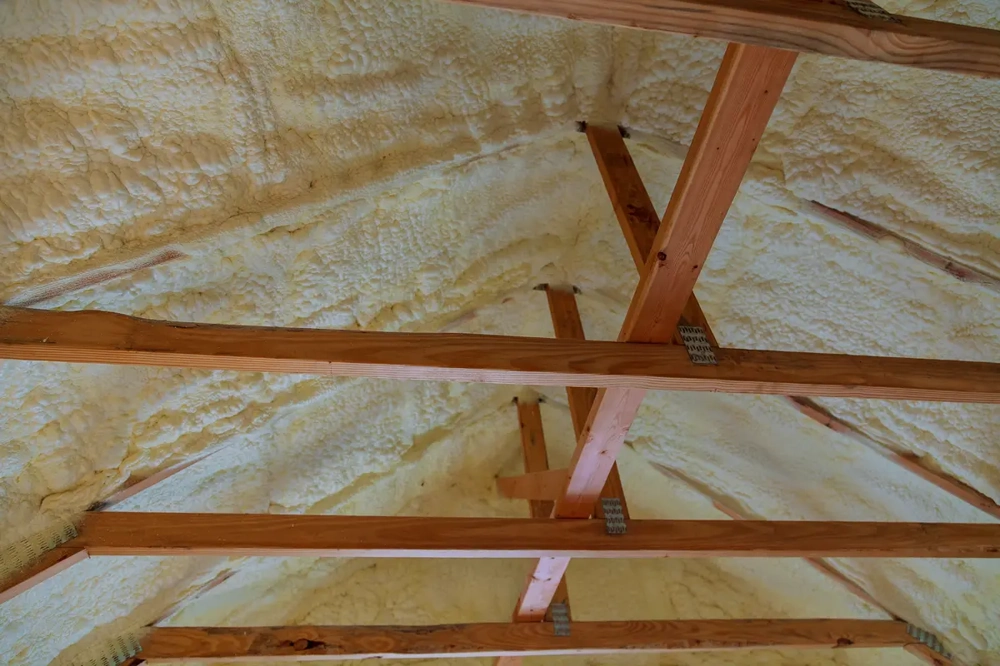 Innenansicht Dachstuhl mit aufgesprühter Dachdämmung auf Dachschrägen und Holzsparren
