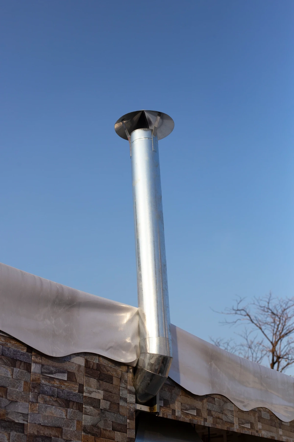 Edelstahl-Kaminverkleidung auf Flachdach mit Steinverblendung