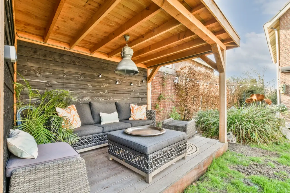 Überdachte Terrasse mit grauer Lounge-Sitzgruppe auf Holzboden – Terrassenüberdachung