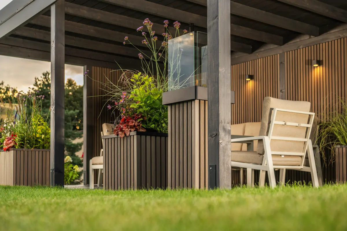 Terrassenüberdachung aus Holz mit gemütlicher Sitzecke und modernen Pflanzkübeln