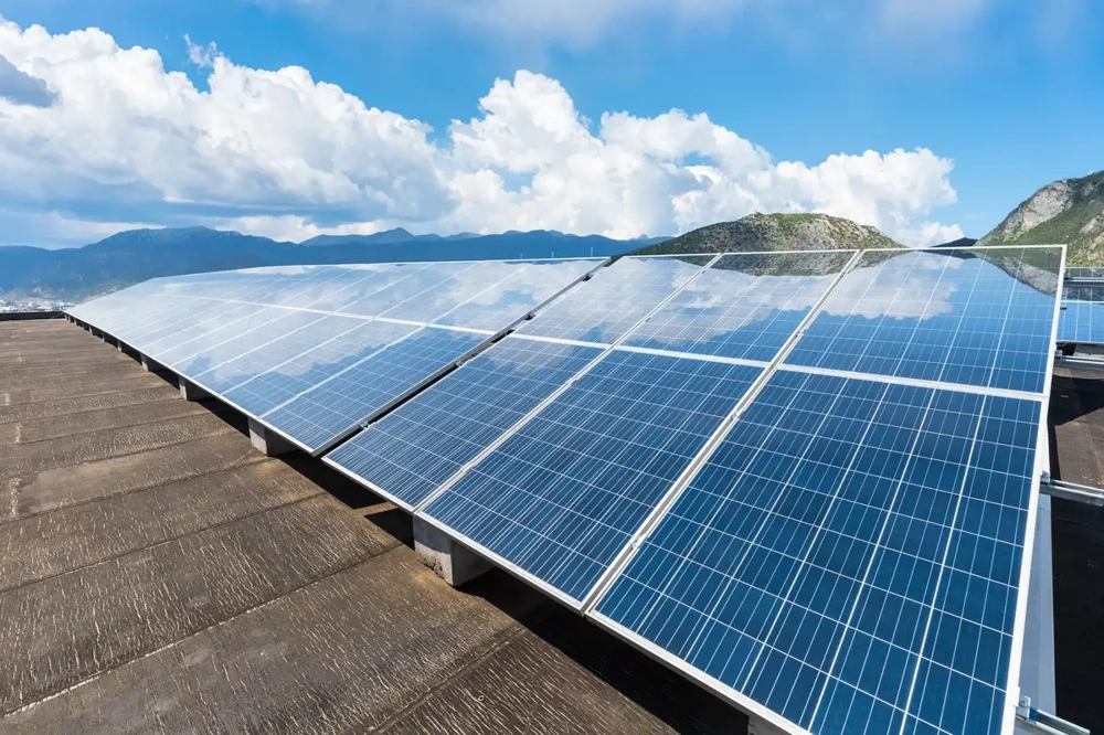 Photovoltaik Dachmontage mit mehreren Solarmodulen auf Flachdach vor Bergkulisse