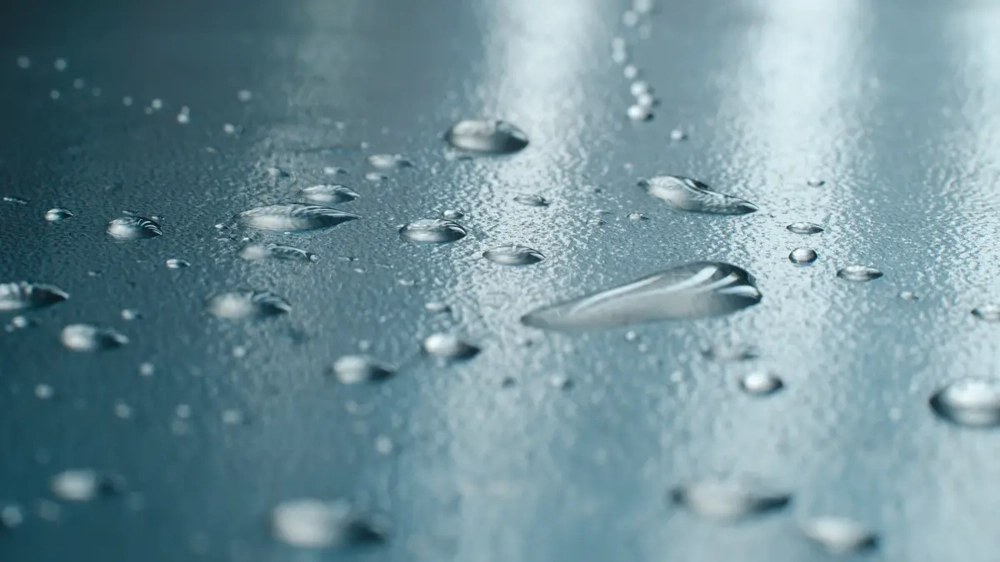 Nahaufnahme von Wassertropfen auf abgedichteter Flachdachoberfläche