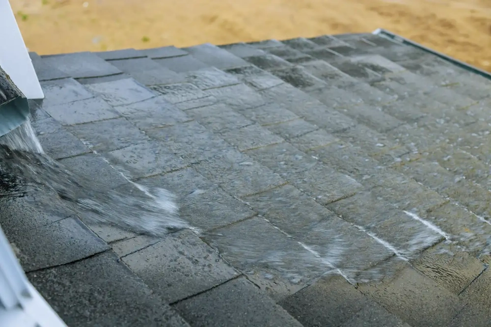 Test des Wasserabflusses nach Dachrinnen Reinigung auf Bitumenschindeldach